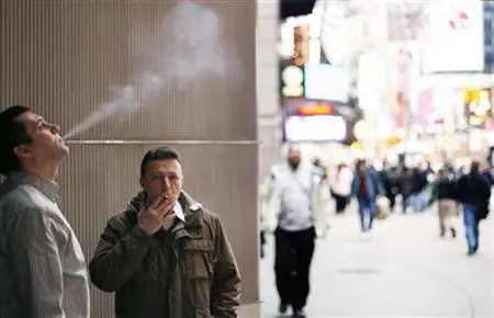 A pair of smokers stand outside of an office building