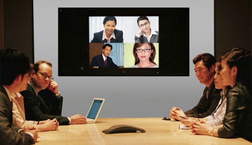 Businesspeople seated around conference table and monitor