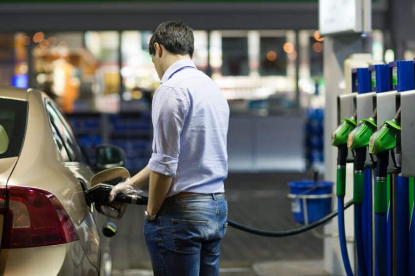 Young man fueling his car at the gas station