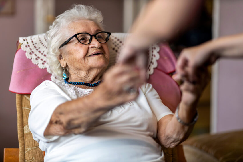 Female,Home,Carer,Supporting,Old,Woman,To,Stand,Up,From